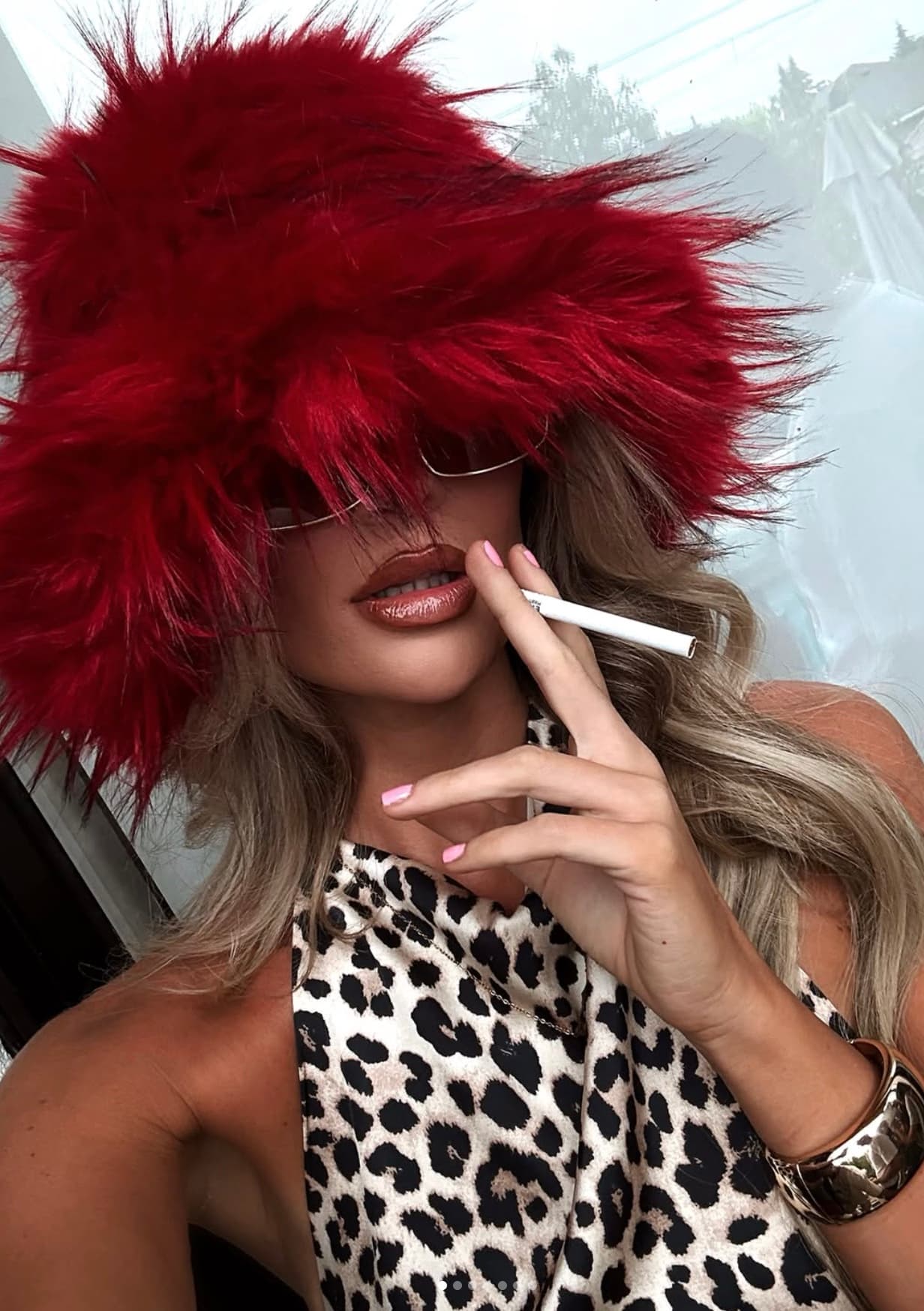 Taylor Spinks in a red faux fur hat and tinted sunglasses